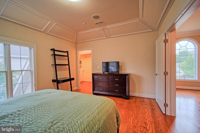 bedroom with light wood finished floors, baseboards, visible vents, and crown molding