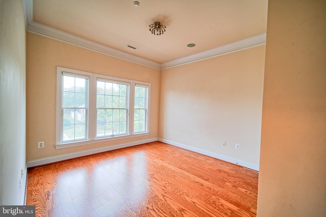 spare room featuring light wood-type flooring, baseboards, visible vents, and crown molding