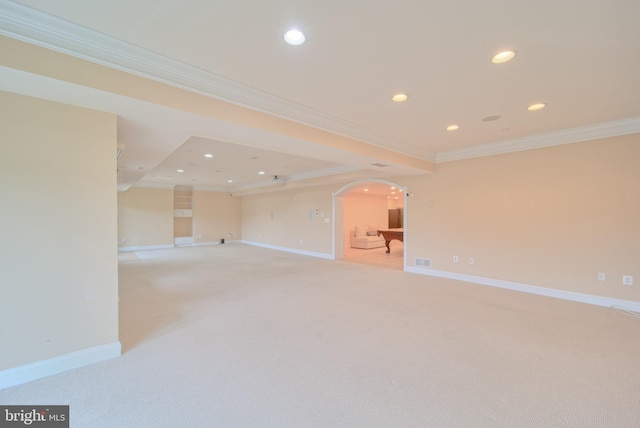 spare room featuring arched walkways, recessed lighting, ornamental molding, light carpet, and baseboards