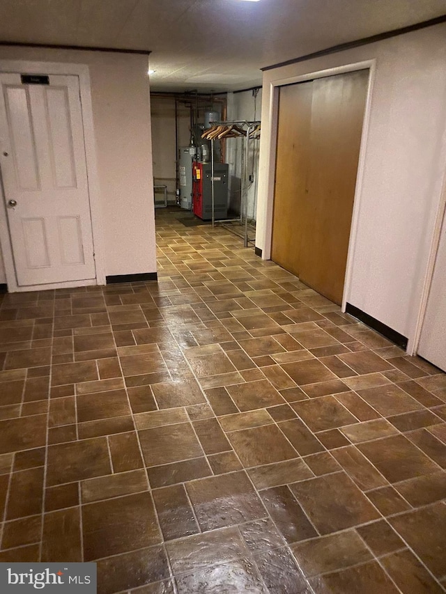 basement featuring water heater, dark tile patterned floors, and heating unit