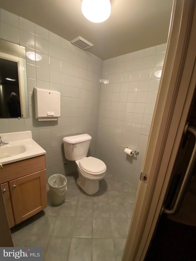 bathroom with tile walls, tile patterned floors, vanity, and toilet