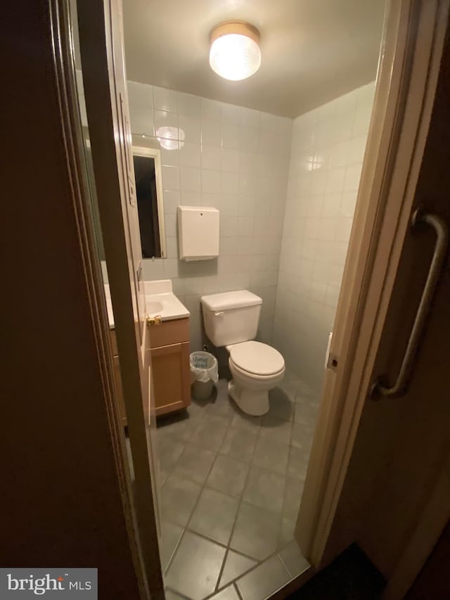 bathroom with tile walls, toilet, vanity, and tile patterned flooring