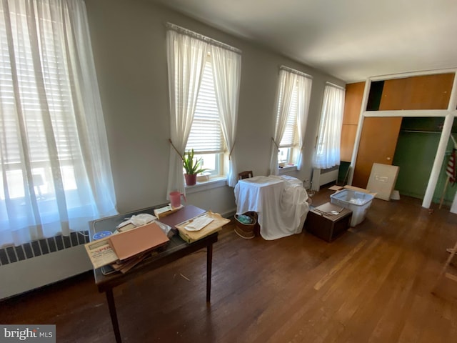 office area with hardwood / wood-style flooring and radiator heating unit