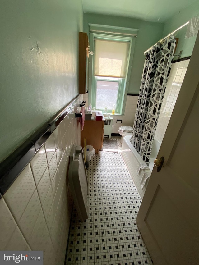 bathroom featuring radiator, shower / bath combo, tile walls, toilet, and tile patterned floors