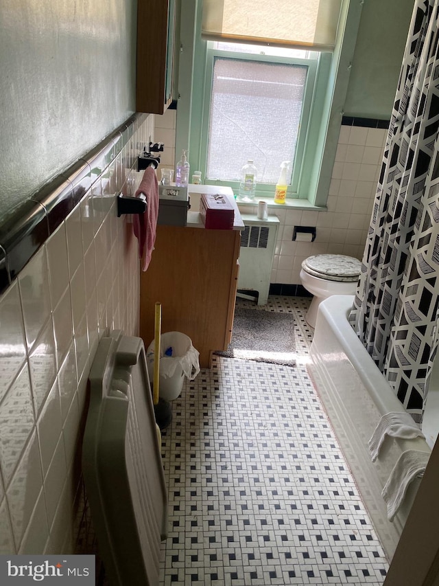 bathroom featuring tile patterned floors, toilet, tile walls, radiator heating unit, and shower / bathtub combination with curtain