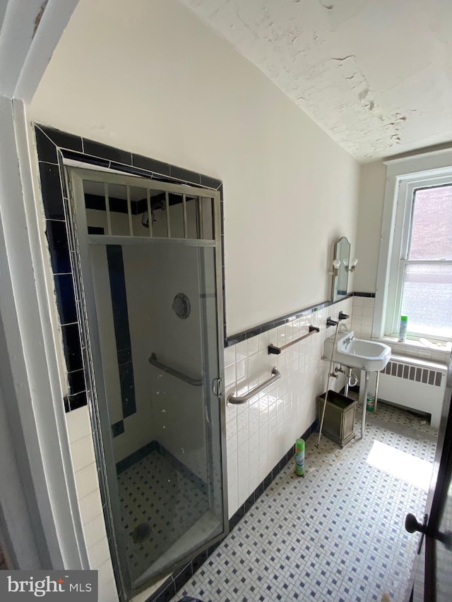 bathroom featuring radiator heating unit, tile patterned floors, tile walls, and a tile shower