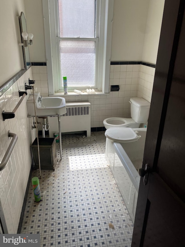 bathroom with radiator, toilet, backsplash, tile patterned flooring, and tile walls