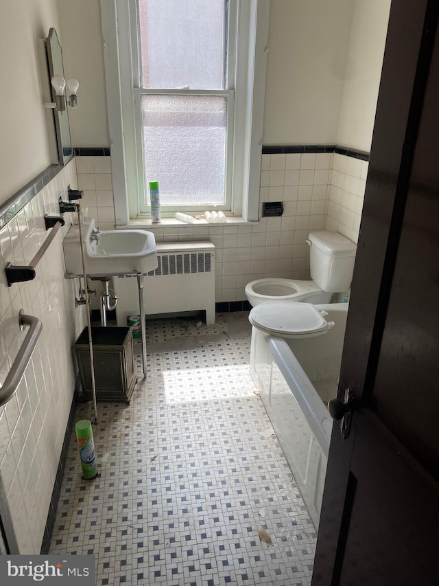 bathroom featuring tile walls, radiator, sink, and toilet