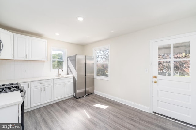 kitchen featuring stainless steel appliances, tasteful backsplash, light hardwood / wood-style flooring, and white cabinetry