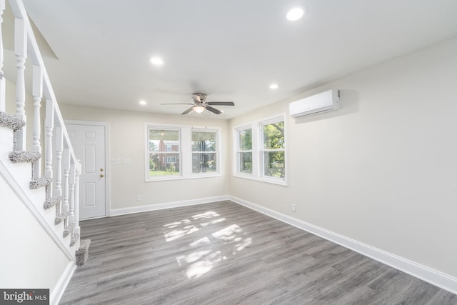 interior space with a wall unit AC, ceiling fan, and wood-type flooring