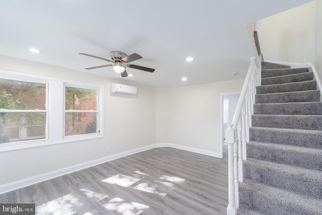 interior space with an AC wall unit, hardwood / wood-style flooring, and ceiling fan