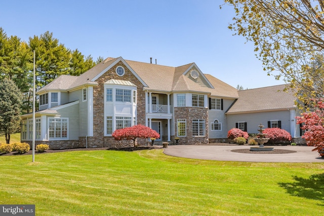 back of property with a yard and a balcony