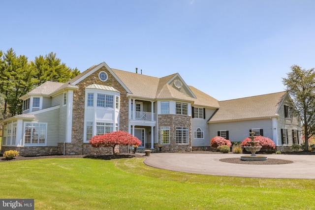 rear view of house featuring a balcony and a lawn