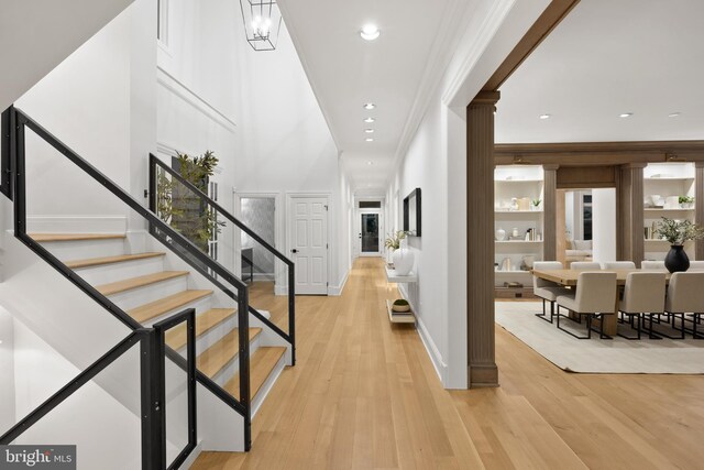 corridor with crown molding, light hardwood / wood-style flooring, and built in shelves