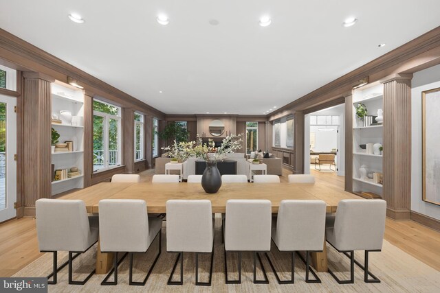 dining space featuring ornamental molding, built in shelves, and light wood-type flooring