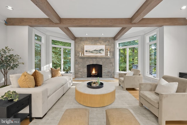 living room featuring light wood-type flooring, beamed ceiling, and a stone fireplace