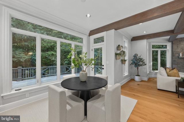 dining space with light wood-type flooring and beam ceiling