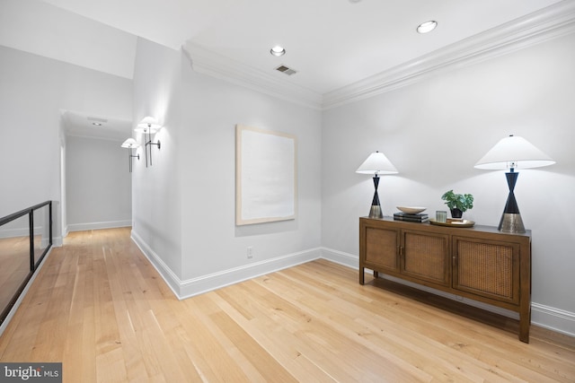 corridor with light wood-type flooring and crown molding