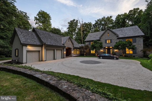 french country home with central air condition unit and a garage