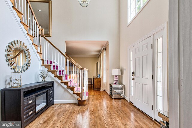 living room featuring ornate columns, crown molding, wood-type flooring, a notable chandelier, and a high end fireplace