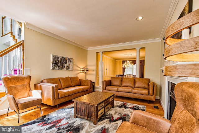 living room featuring ornate columns, ornamental molding, hardwood / wood-style flooring, and a notable chandelier