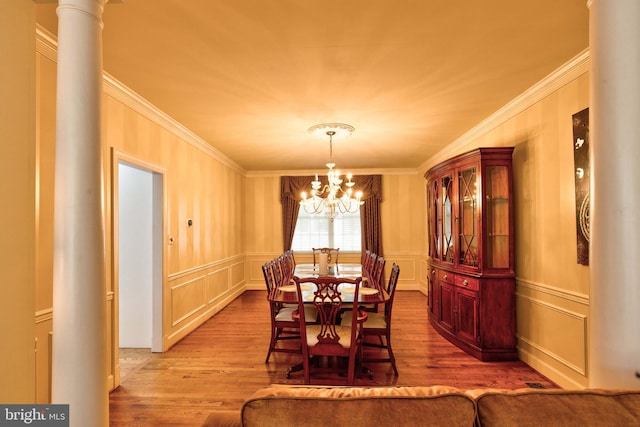 dining space with an inviting chandelier, ornamental molding, decorative columns, and light hardwood / wood-style flooring