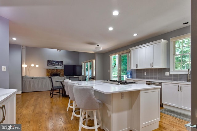 kitchen featuring white cabinetry, stainless steel gas cooktop, a kitchen island, and light wood-type flooring