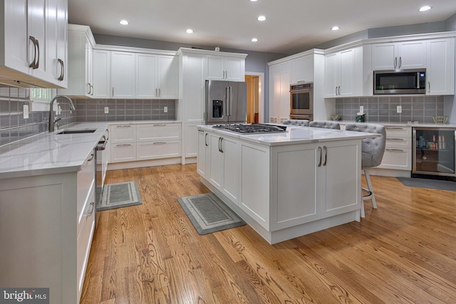 kitchen featuring light stone counters, stainless steel appliances, a center island, and white cabinets