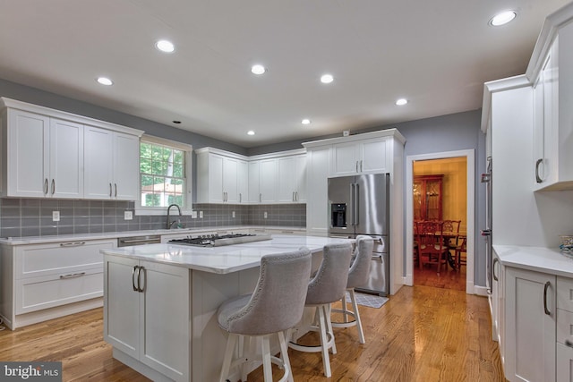 kitchen featuring appliances with stainless steel finishes, a center island, light hardwood / wood-style flooring, and white cabinets