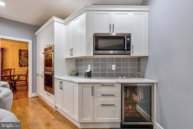 kitchen featuring wine cooler, stainless steel appliances, and white cabinets