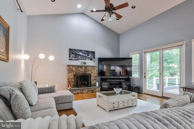 living room featuring hardwood / wood-style flooring, a fireplace, high vaulted ceiling, and ceiling fan