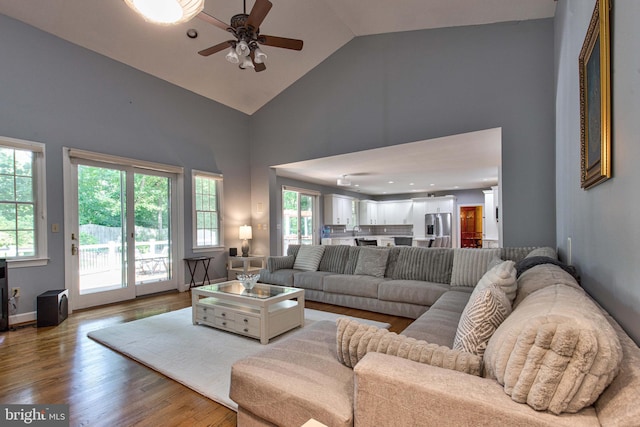 living room with ceiling fan, wood-type flooring, and high vaulted ceiling