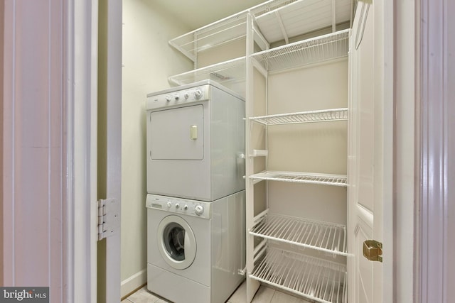 laundry room featuring stacked washer and clothes dryer and light tile patterned flooring