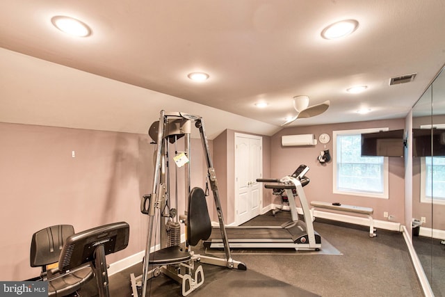 exercise area featuring a wall mounted air conditioner and vaulted ceiling