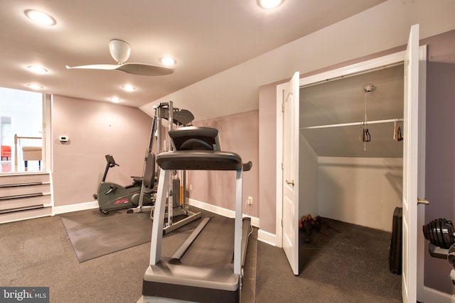 workout area with vaulted ceiling, ceiling fan, and dark colored carpet