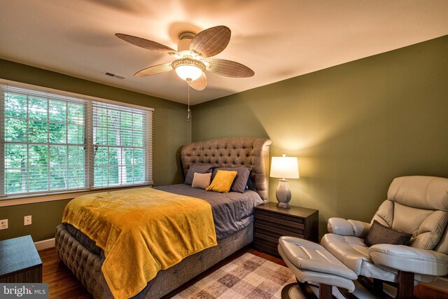 unfurnished bedroom featuring ceiling fan, hardwood / wood-style floors, multiple closets, and ensuite bathroom