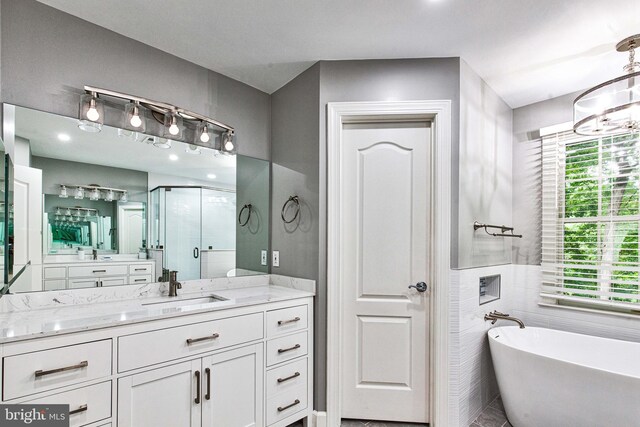 bathroom featuring a notable chandelier, vanity, independent shower and bath, and a wealth of natural light