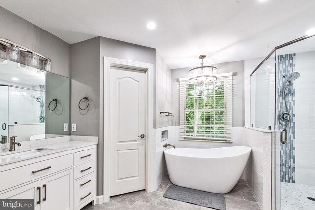 bathroom featuring plus walk in shower, tile walls, vanity, and a chandelier