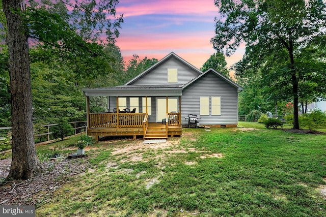 back house at dusk featuring a lawn and a wooden deck