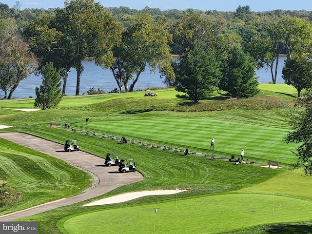 surrounding community with a water view and a lawn