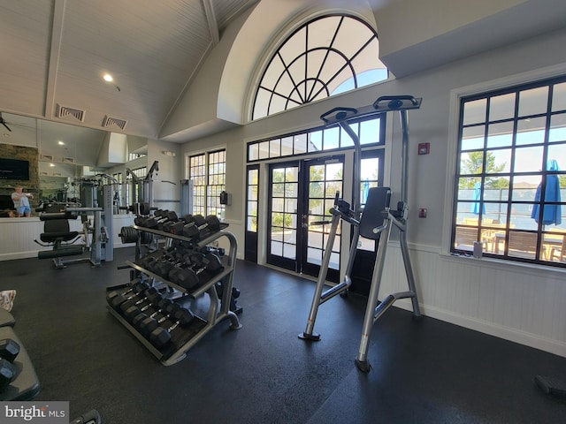 exercise room with high vaulted ceiling and french doors