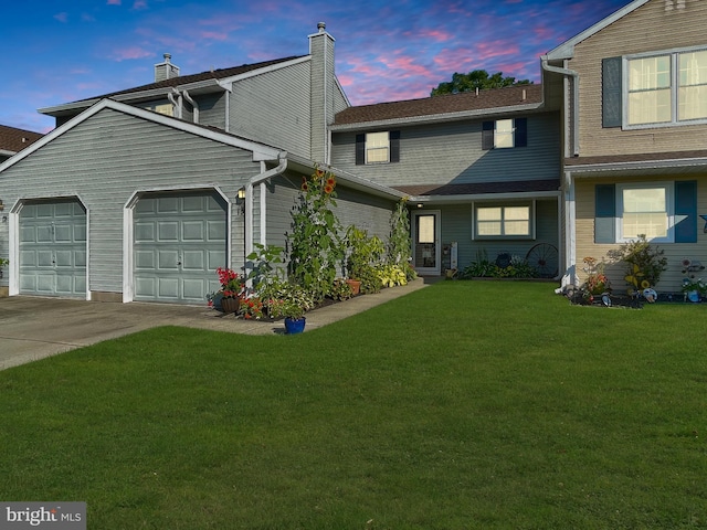 view of front facade with driveway, a chimney, an attached garage, and a front yard