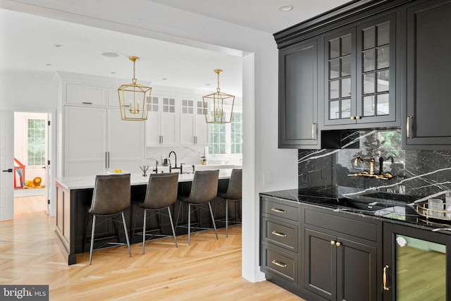 kitchen with tasteful backsplash, light parquet flooring, a kitchen breakfast bar, dark stone countertops, and hanging light fixtures