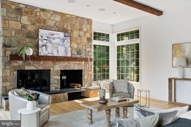 living room with a wealth of natural light, light hardwood / wood-style floors, and a stone fireplace