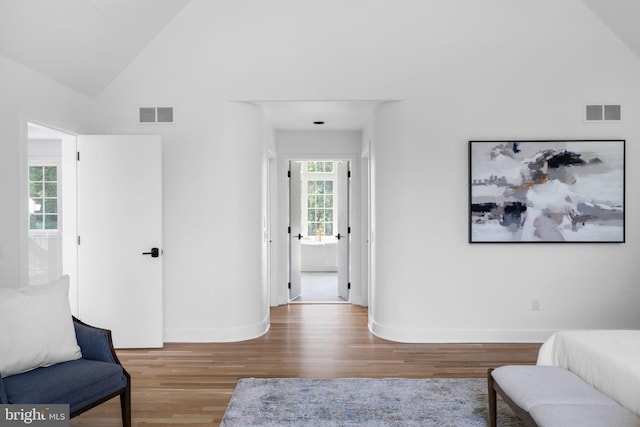 living area featuring high vaulted ceiling and wood-type flooring