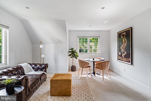 living area with light colored carpet, plenty of natural light, and lofted ceiling