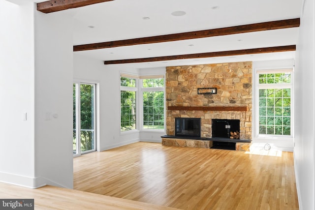 unfurnished living room with a fireplace, light hardwood / wood-style floors, and beam ceiling