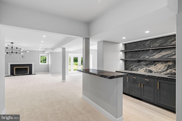 bar featuring light colored carpet, backsplash, and a chandelier