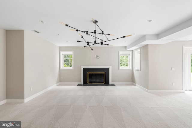 unfurnished living room with an inviting chandelier, plenty of natural light, and light colored carpet