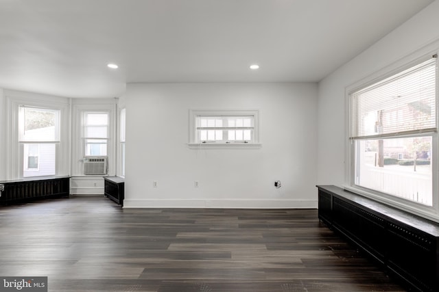 unfurnished room with radiator, a healthy amount of sunlight, baseboards, and dark wood-style floors